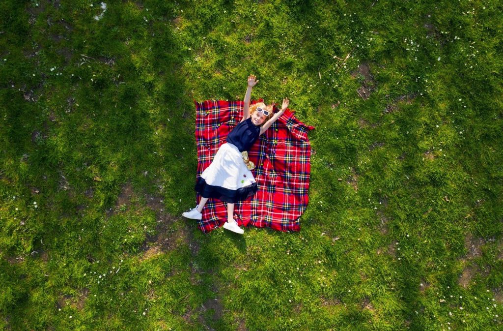 girl lying on flannel blanket with her arms outstretched